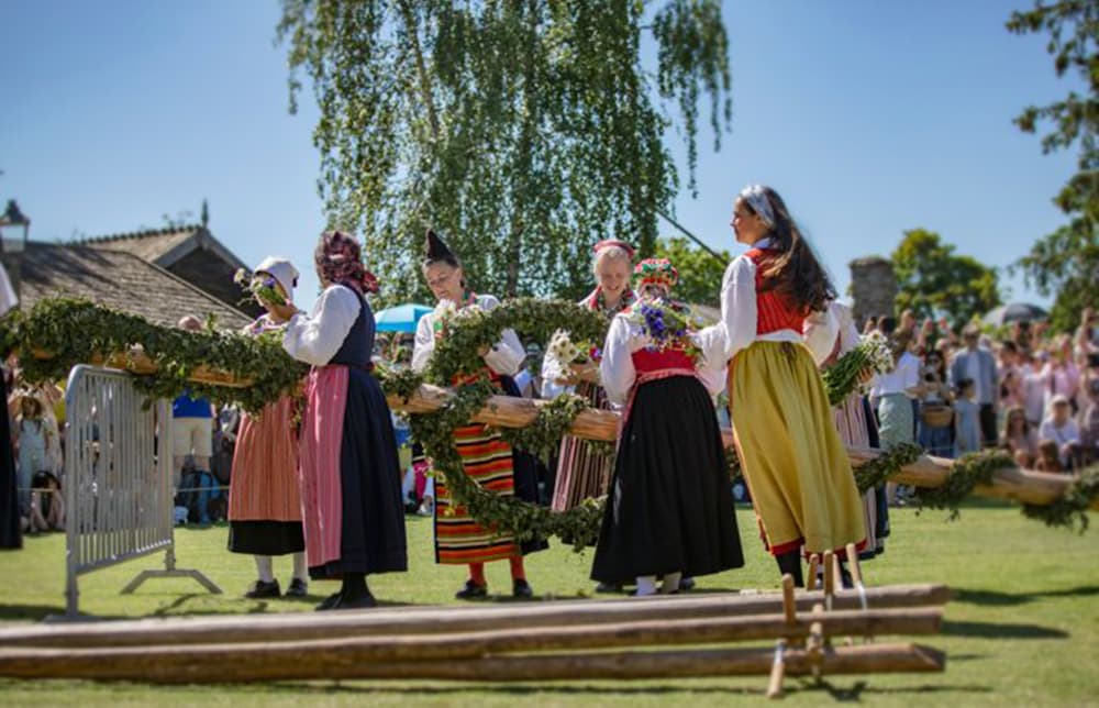 Midsommar celebration at Skansen with decorated maypole and people dancing